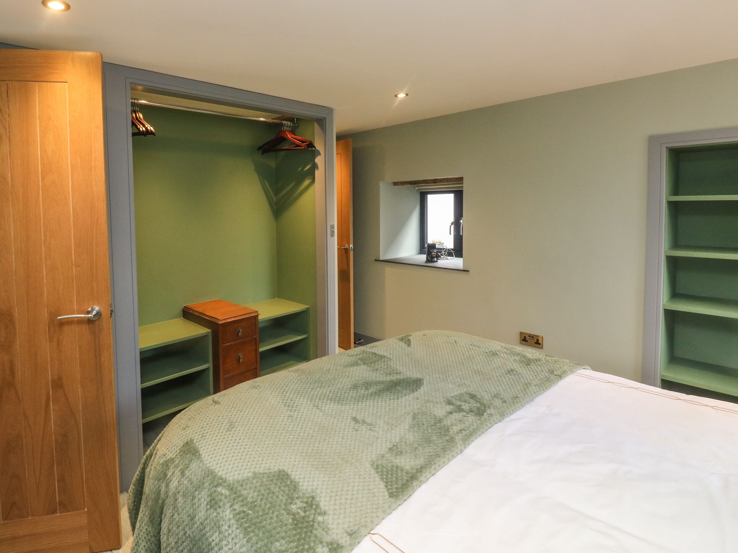 Ein Schlafzimmer mit einem Bett, einem Kleiderschrank und einem kleinen Fenster.