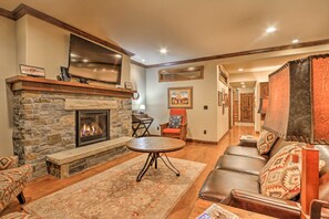 A cozy living room with a stone fireplace, leather sofa, and a flat-screen TV mounted above it.