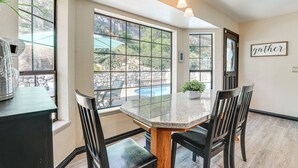 Comedor con una mesa grande, sillas y vistas a una piscina al aire libre.