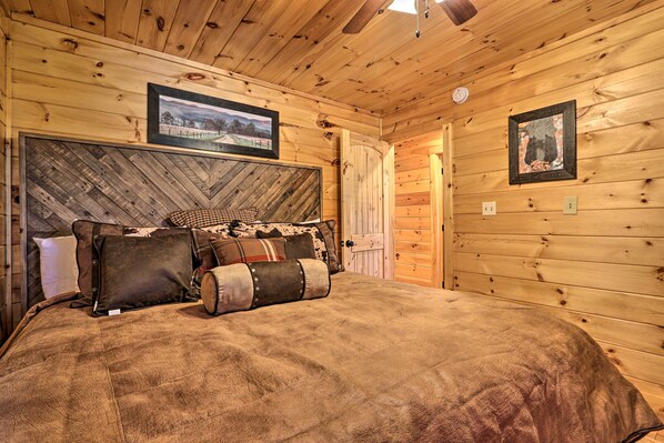 Une chambre confortable dans un chalet en bois, avec un grand lit, une tête de lit en bois et deux tableaux encadrés accrochés aux murs.