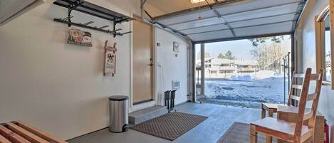 A garage with a wooden bench, a metal shelf, a welcome sign, and a view of a snowy landscape.
