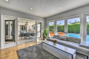 A modern living room with a sofa, coffee table, and a view of a swimming pool.