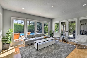 A modern living room with a sofa, coffee table, and large windows.