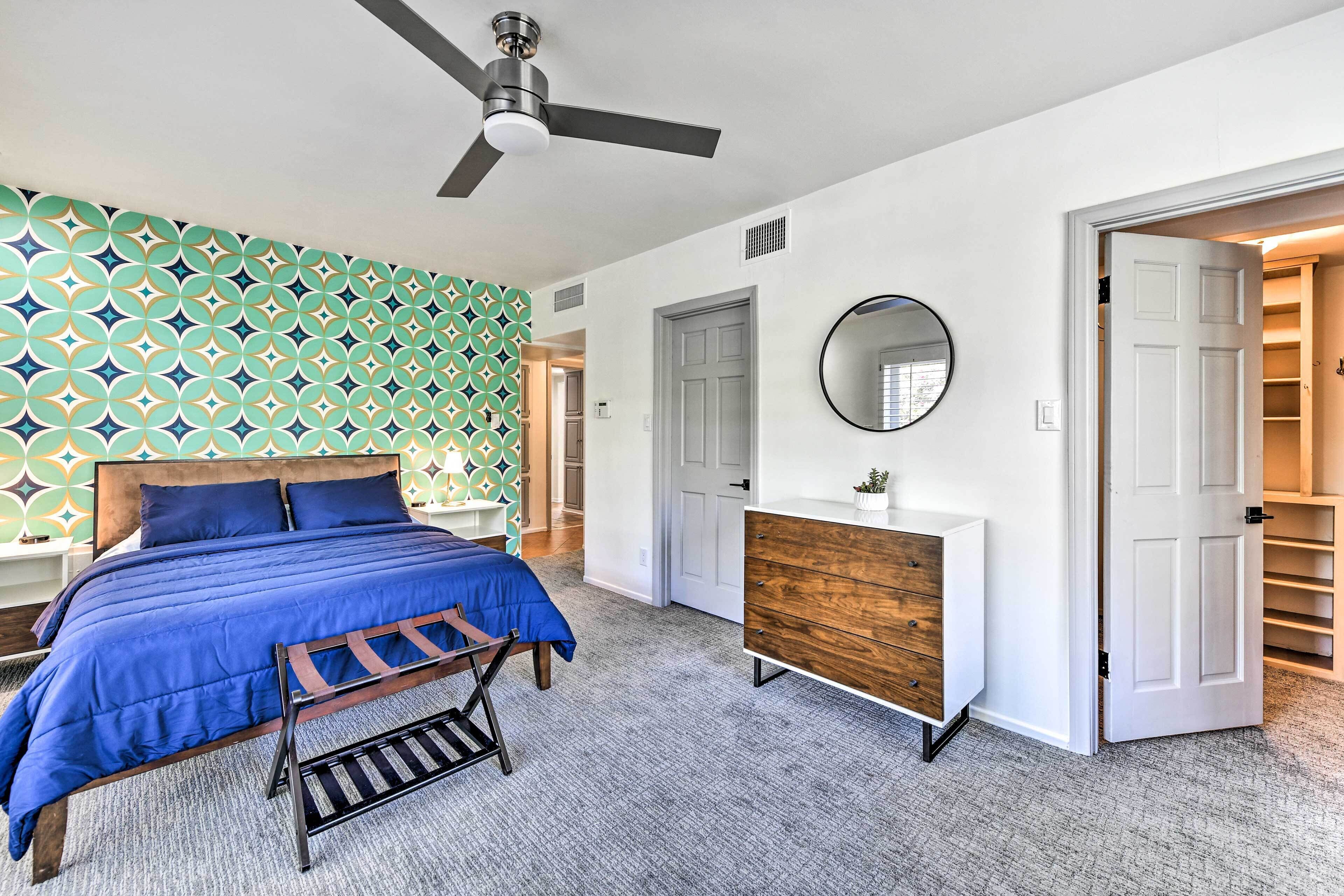 A bedroom with a bed, a dresser, a ceiling fan, a mirror, and a walk-in closet.