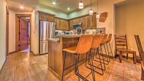 Une cuisine avec des meubles en bois, des appareils électroménagers en acier inoxydable et des tabourets de bar.