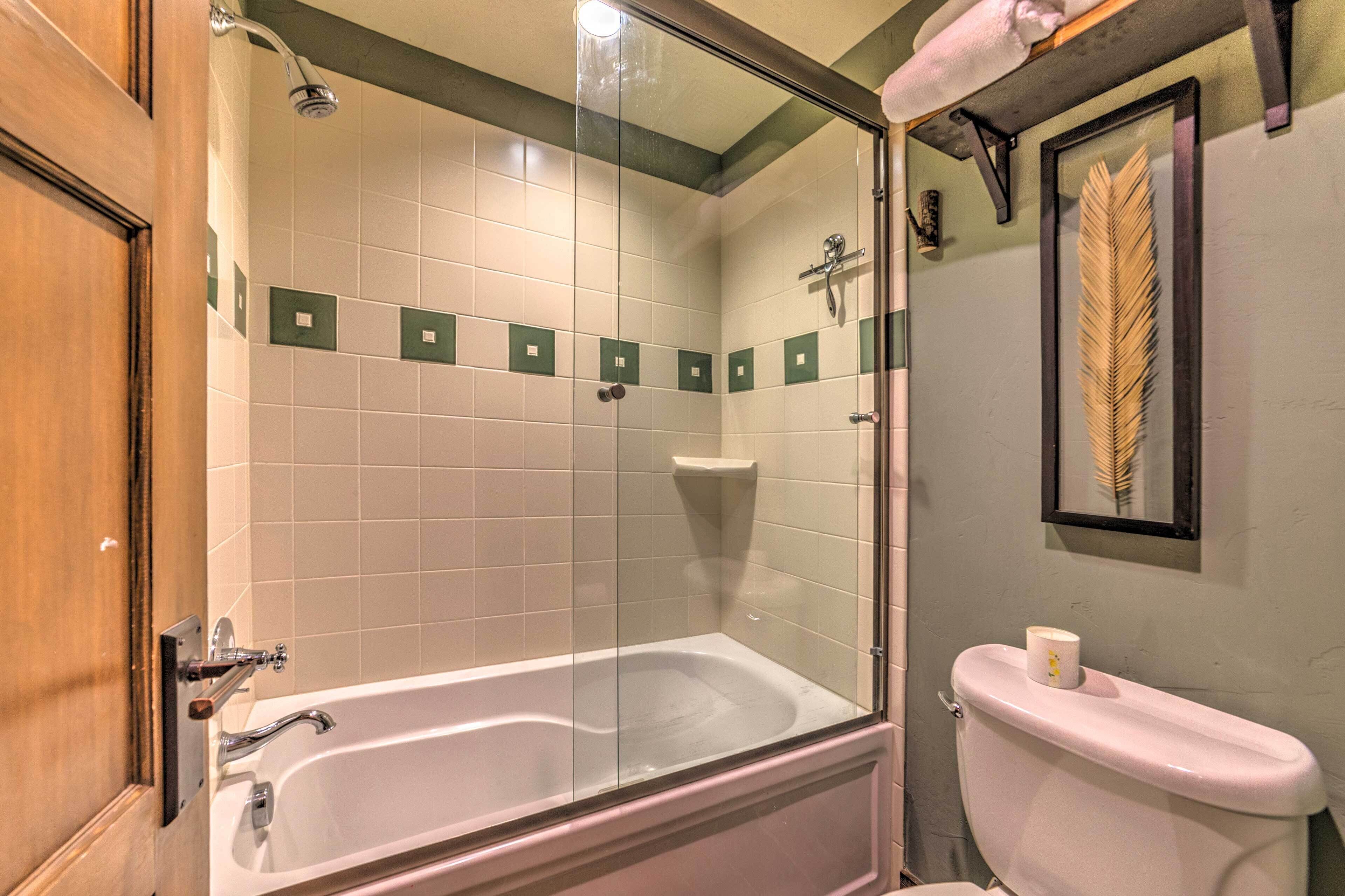Un baño con ducha envuelta en vidrio, una bañera blanca y un inodoro.