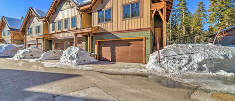 A multi-story wooden building with large garage doors, surrounded by snow.