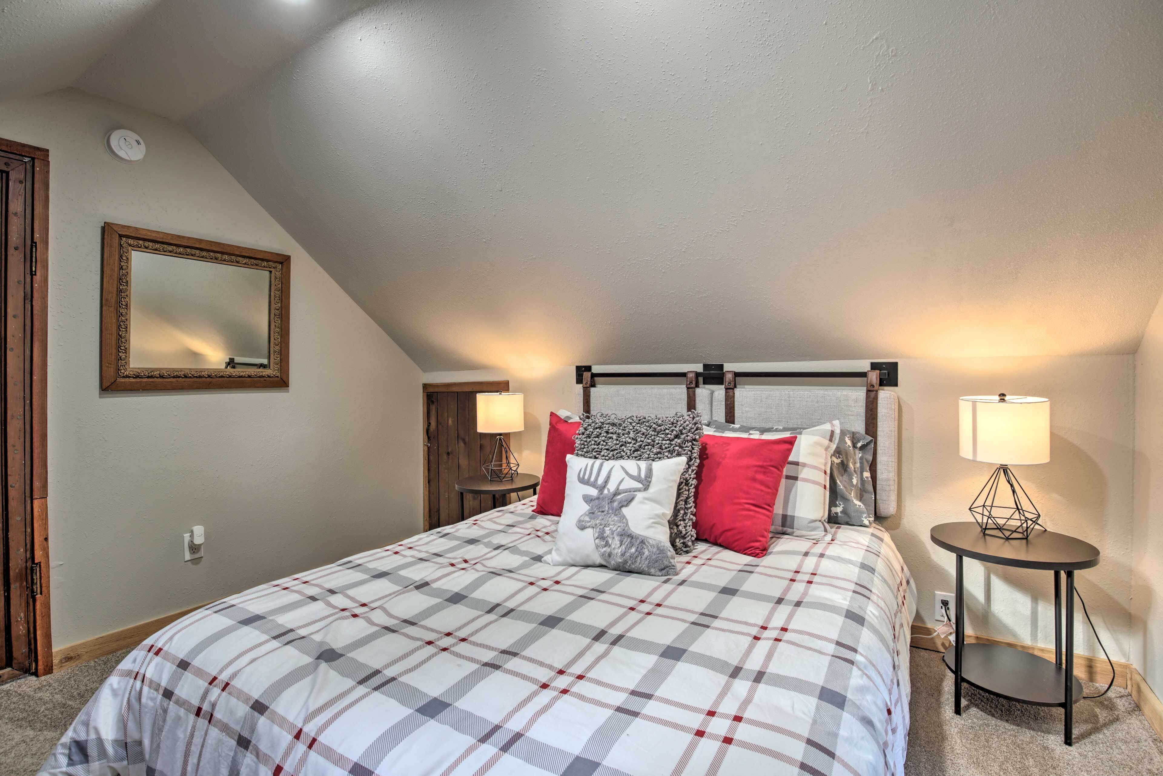 Une chambre à coucher avec une couvre-lit à carreaux, un miroir, deux tables de chevet avec des lampes et une porte en bois.