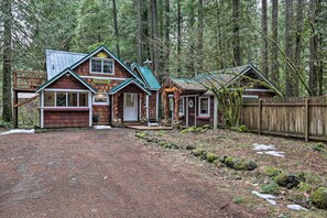 Une cabane rustique avec une façade en bois, un toit en métal et une allée gravillonnée.
