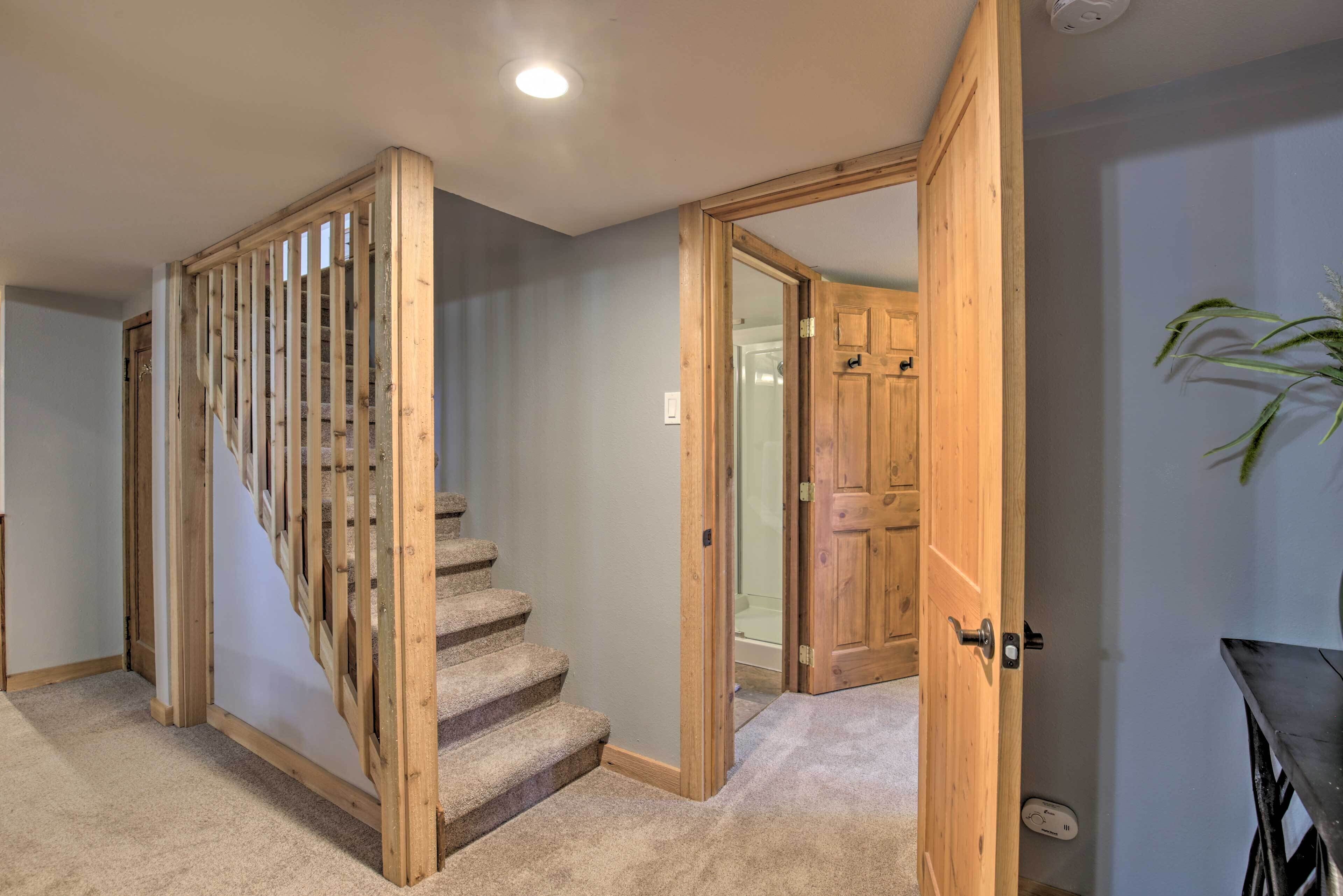 Un escalier en bois, dont les marches sont recouvertes de moquette, mène à une pièce dotée d’une porte en bois et ornée d’une plante sur le mur.