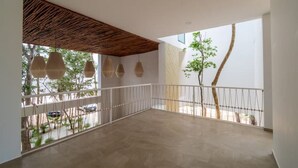 Ein geräumiger Balkon mit Holzboden, weißen Geländern und hängenden Pendelleuchten.
