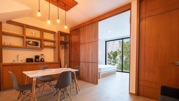 Eine moderne Küche mit Essbereich, Holzböden und einer großen Schiebetür zum Balkon.