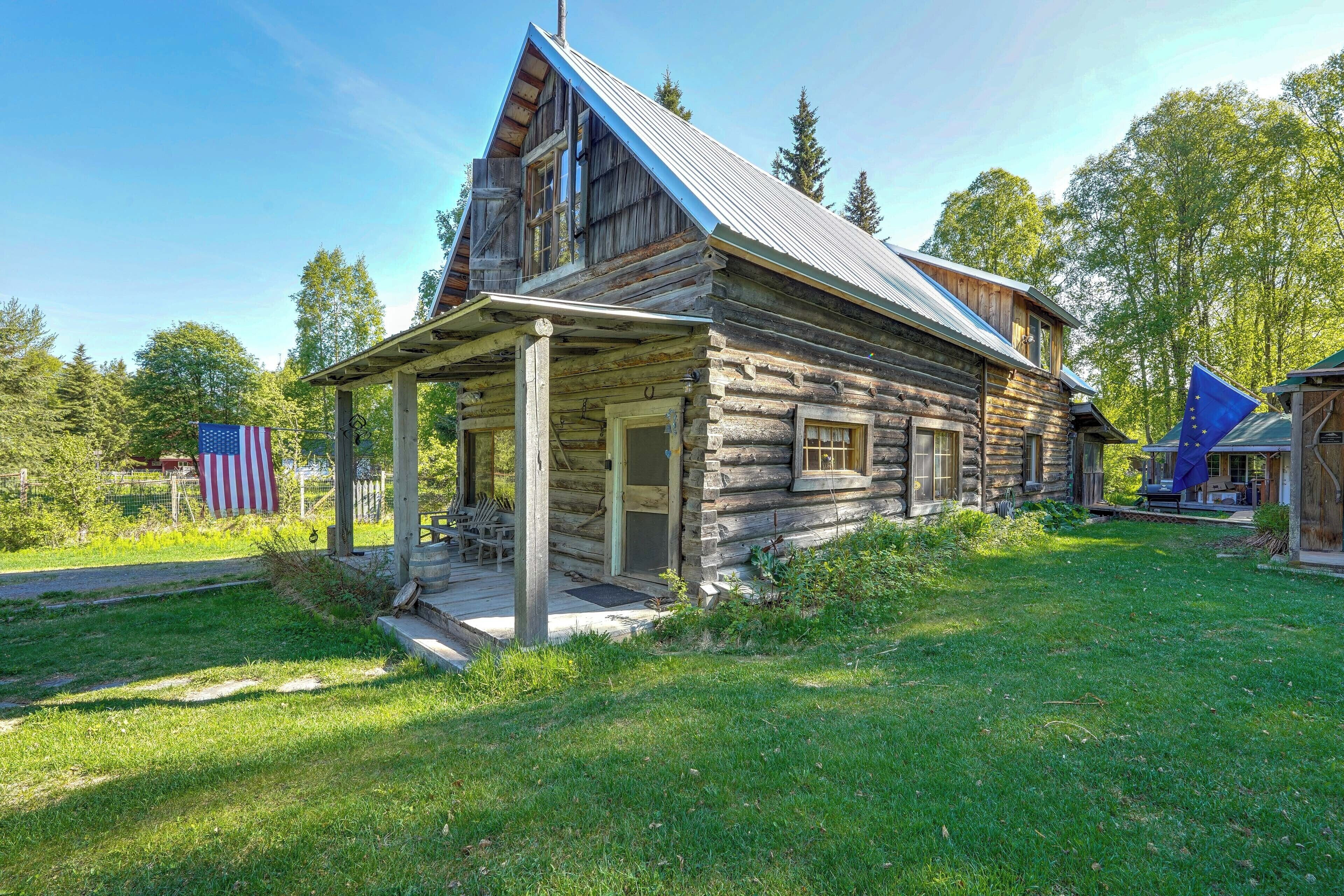 A rustic log cabin with a porch and a chimney.