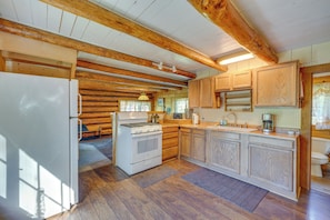 A kitchen with wooden cabinets, a stove, and a refrigerator. - Historic Century-old Cabin in Downtown Hope (Hope)