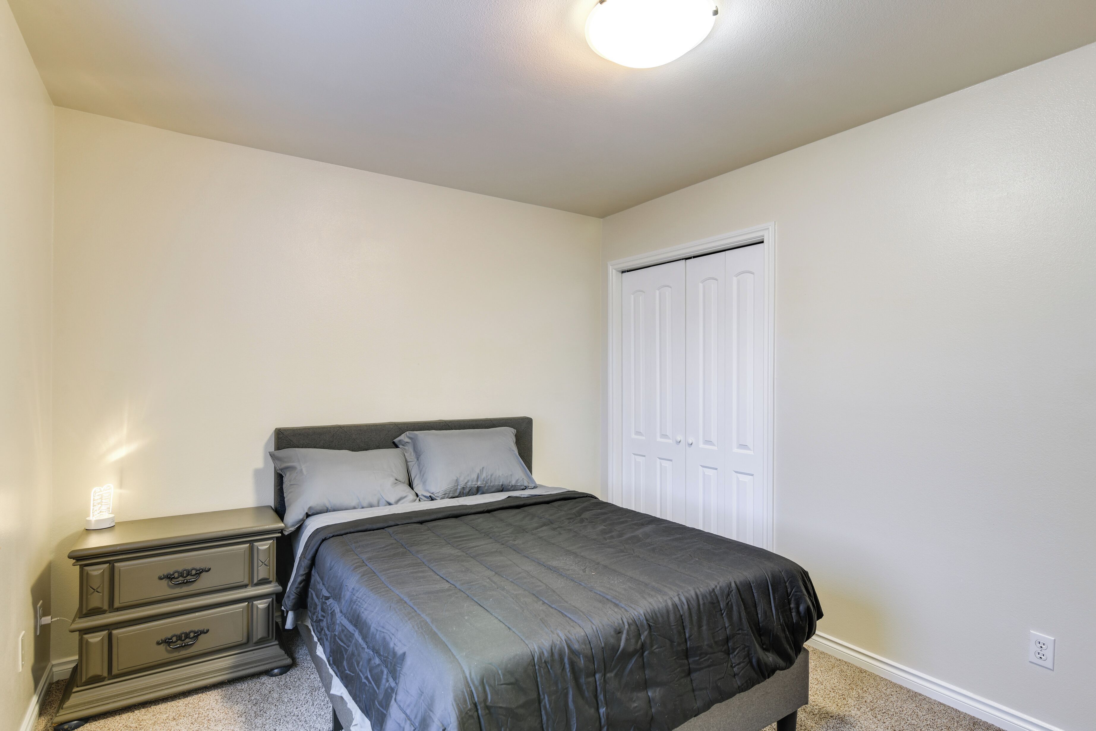 Un dormitorio con cama, mesita de noche, cómoda y armario.
