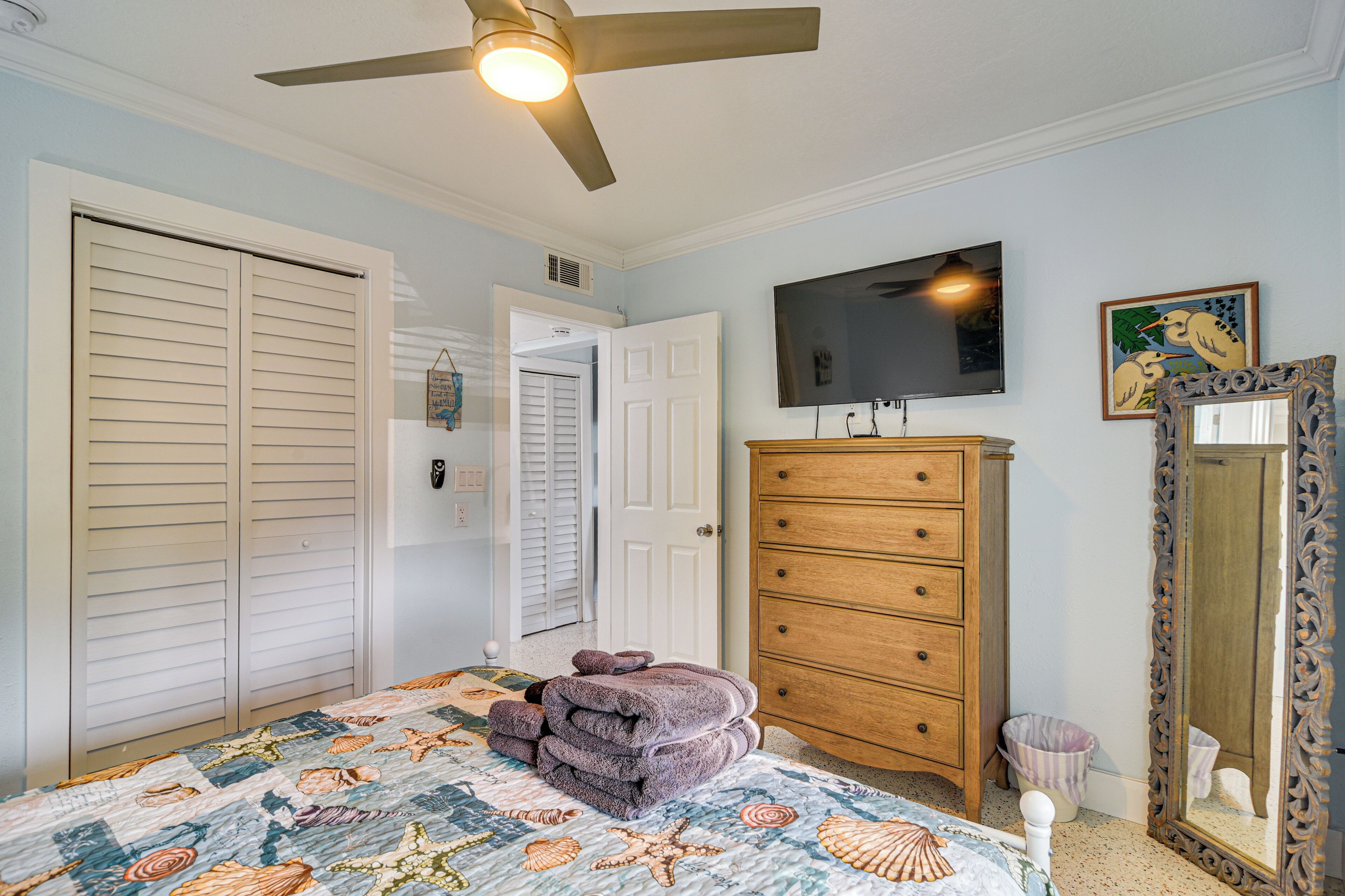 Un dormitorio con cama, cómoda, televisor y espejo.