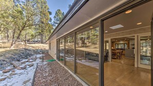 Une maison moderne dotée de grandes portes vitrées qui donnent sur un espace salle à manger et une cuisine.