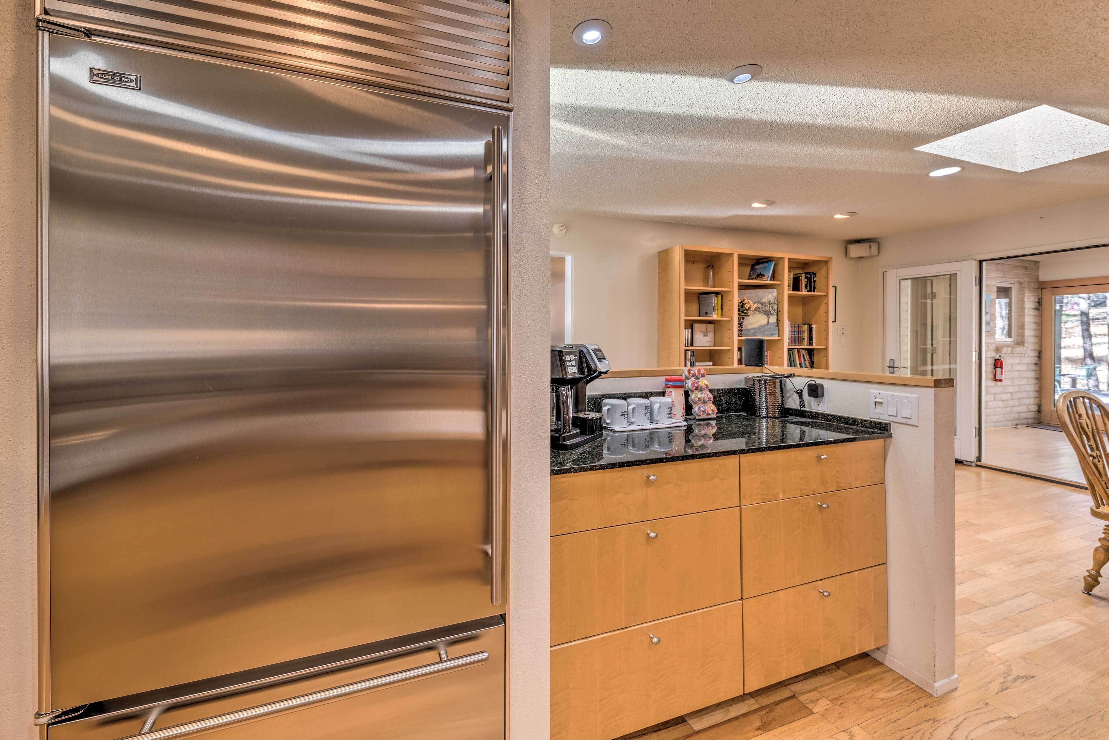 A modern kitchen with a stainless steel refrigerator, wooden cabinets, and a countertop with various appliances.