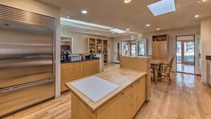 Une cuisine moderne avec des meubles en bois, un réfrigérateur en acier inoxydable et un îlot central doté d’une planche à découper.
