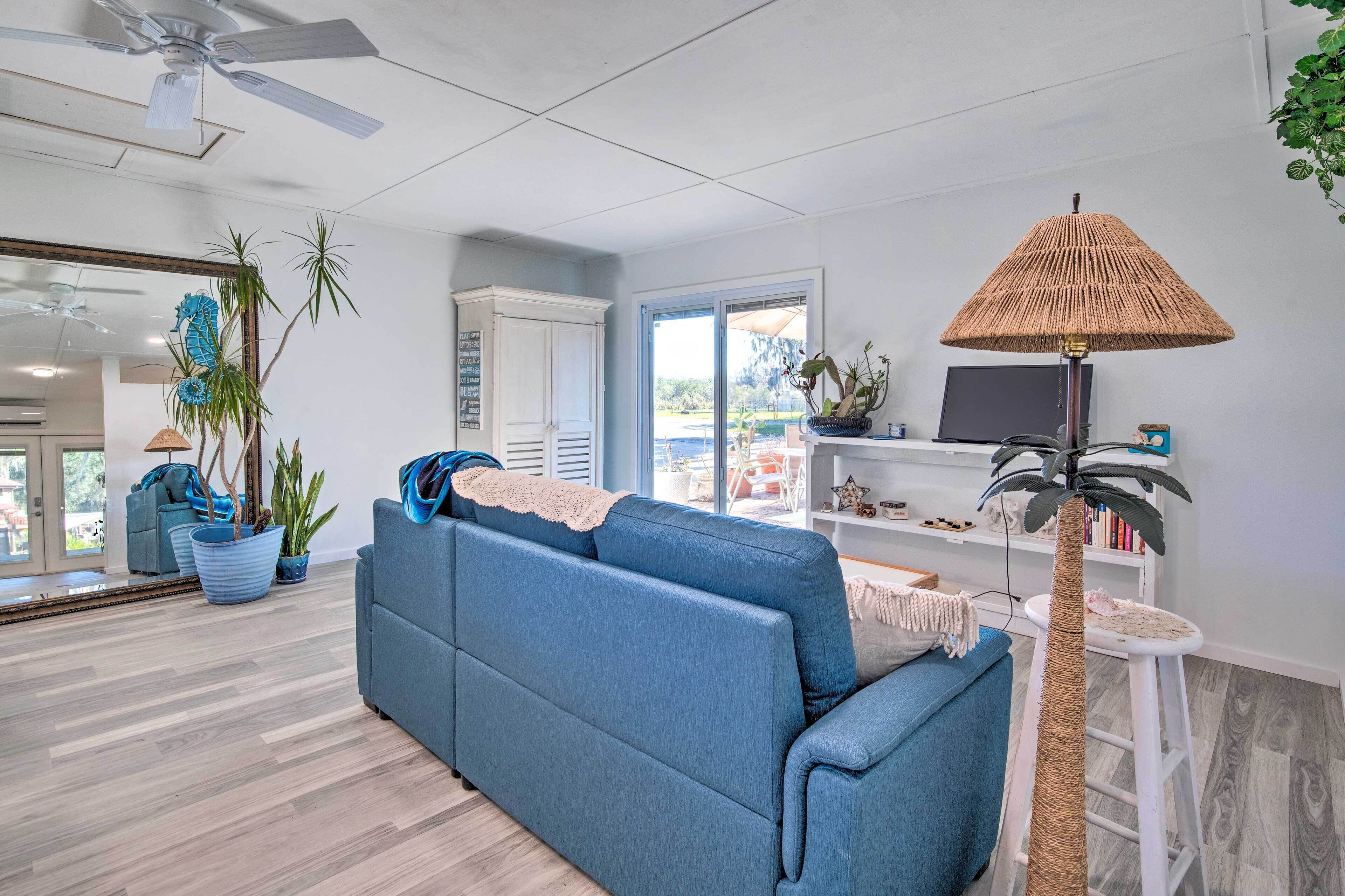 A modern living room with a blue sofa, a tall floor lamp, and a large mirror.