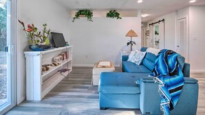 Un salon moderne avec un canapé bleu, une bibliothèque blanche et une petite table.