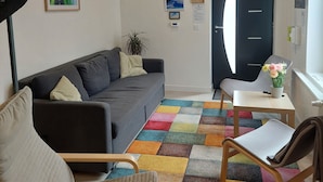 Una sala de estar moderna con un sofá, una silla, una mesita y una alfombra colorida.