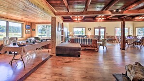 A spacious room with wooden floors, a long dining table, and a cozy seating area. - Family Home w/ Stunning River & Mountain View (Priest River)