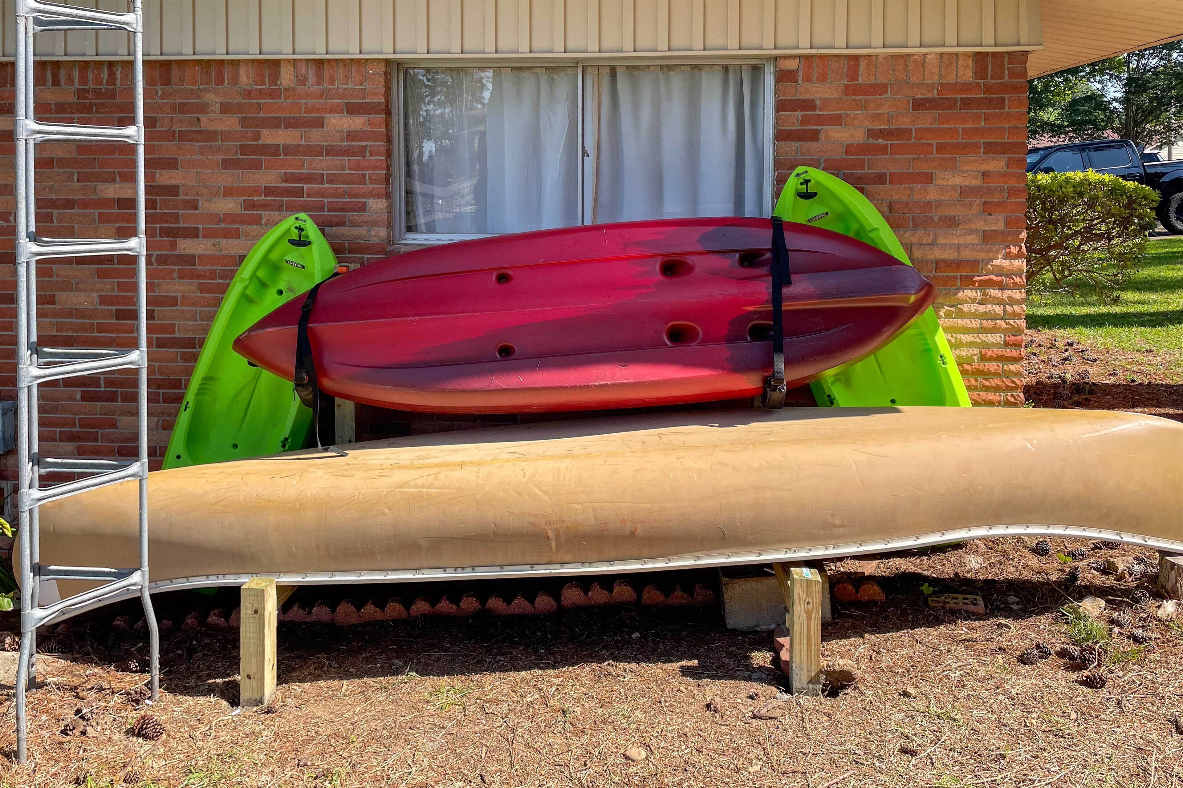 A slide with kayaks and a ladder against a brick building.