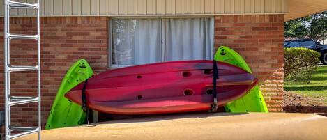 A slide with kayaks and a ladder against a brick building.