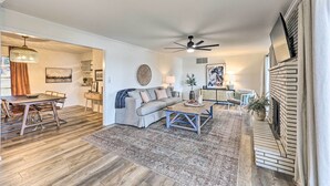 A spacious living room with a sofa, coffee table, and fireplace. - Waterfront Home w/ Dock > 3 Mi to Oaklawn Racing! (Hot Springs)