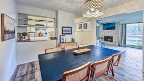 A modern dining area with a large table, wooden chairs, and a hanging light fixture. - Waterfront Home w/ Dock > 3 Mi to Oaklawn Racing! (Hot Springs)