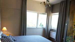 Una camera da letto con un letto, una lampada, una finestra e delle tende.