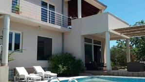 Una casa a due piani con piscina, patio coperto e balcone.