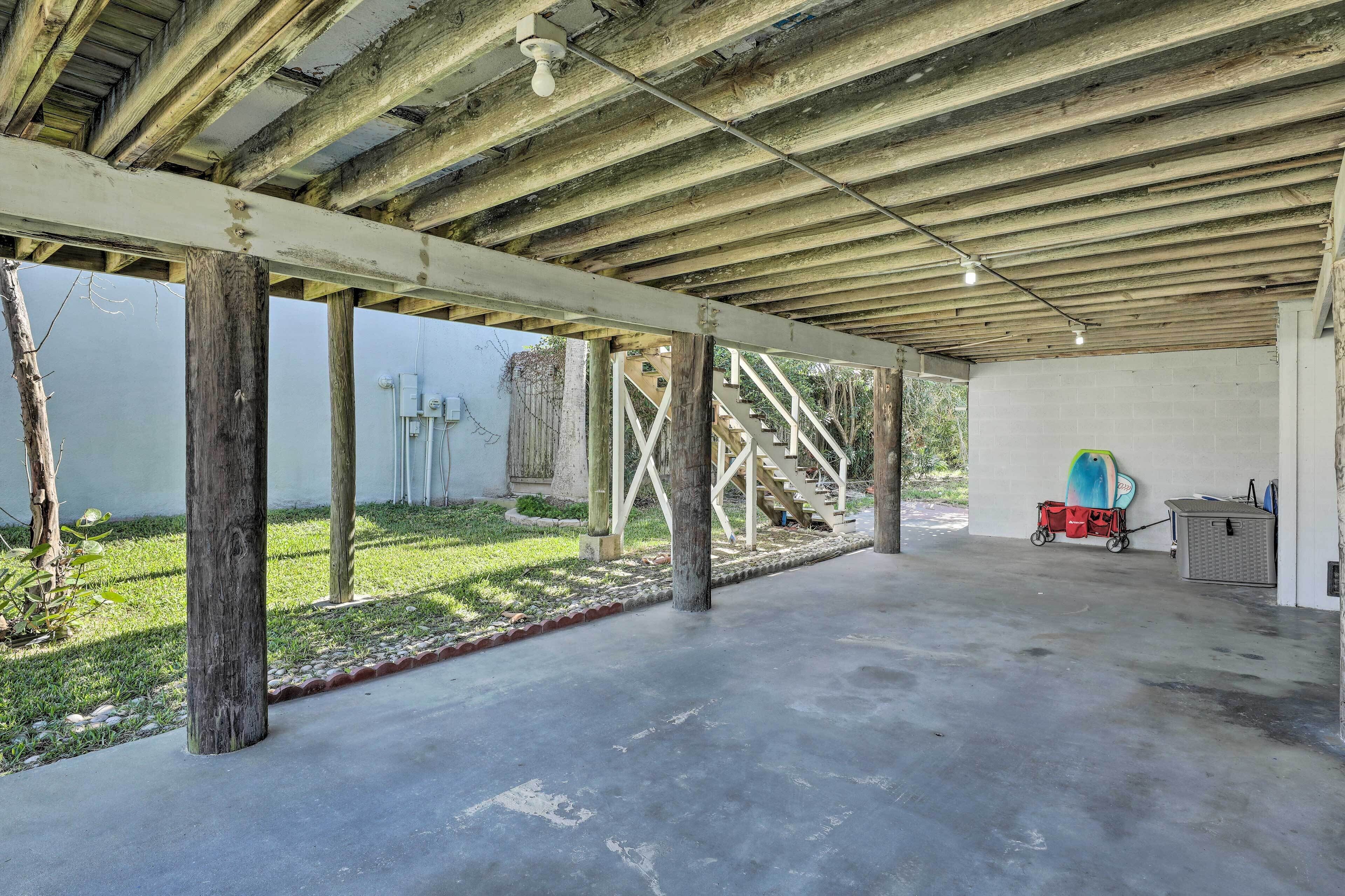 Espacio abierto e inacabado con vigas de madera a la vista y suelo de hormigón, con una escalera que lleva a un nivel superior.