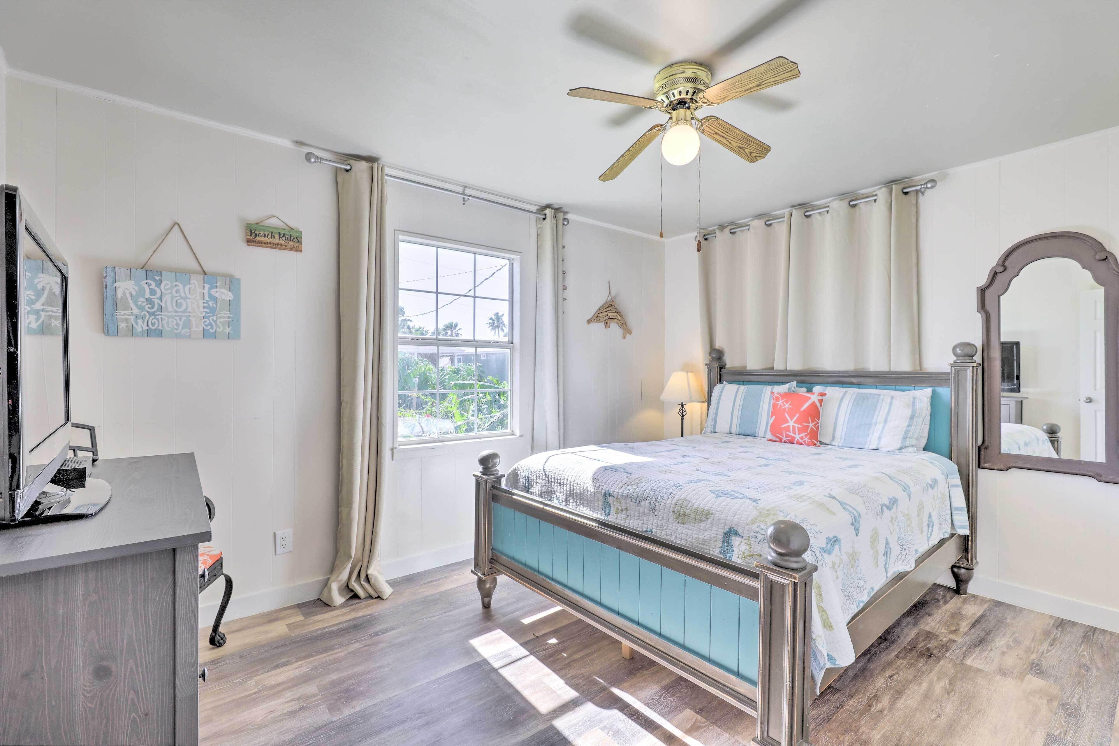 A bedroom with a bed, a ceiling fan, a window, and a desk.