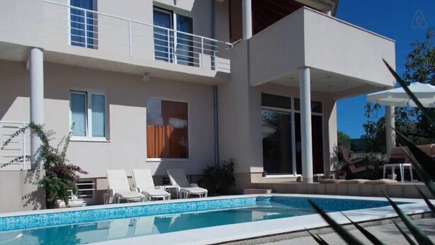 A modern two-story building with a swimming pool, white balconies, and lounge chairs. - Apartments Villa Dona - Superior Double Room (Vela Luka)
