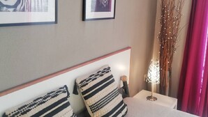 Hotelkamer met een bed, twee zebra kunstwerken in lijsten, een bedlamp en een vaas met takken.