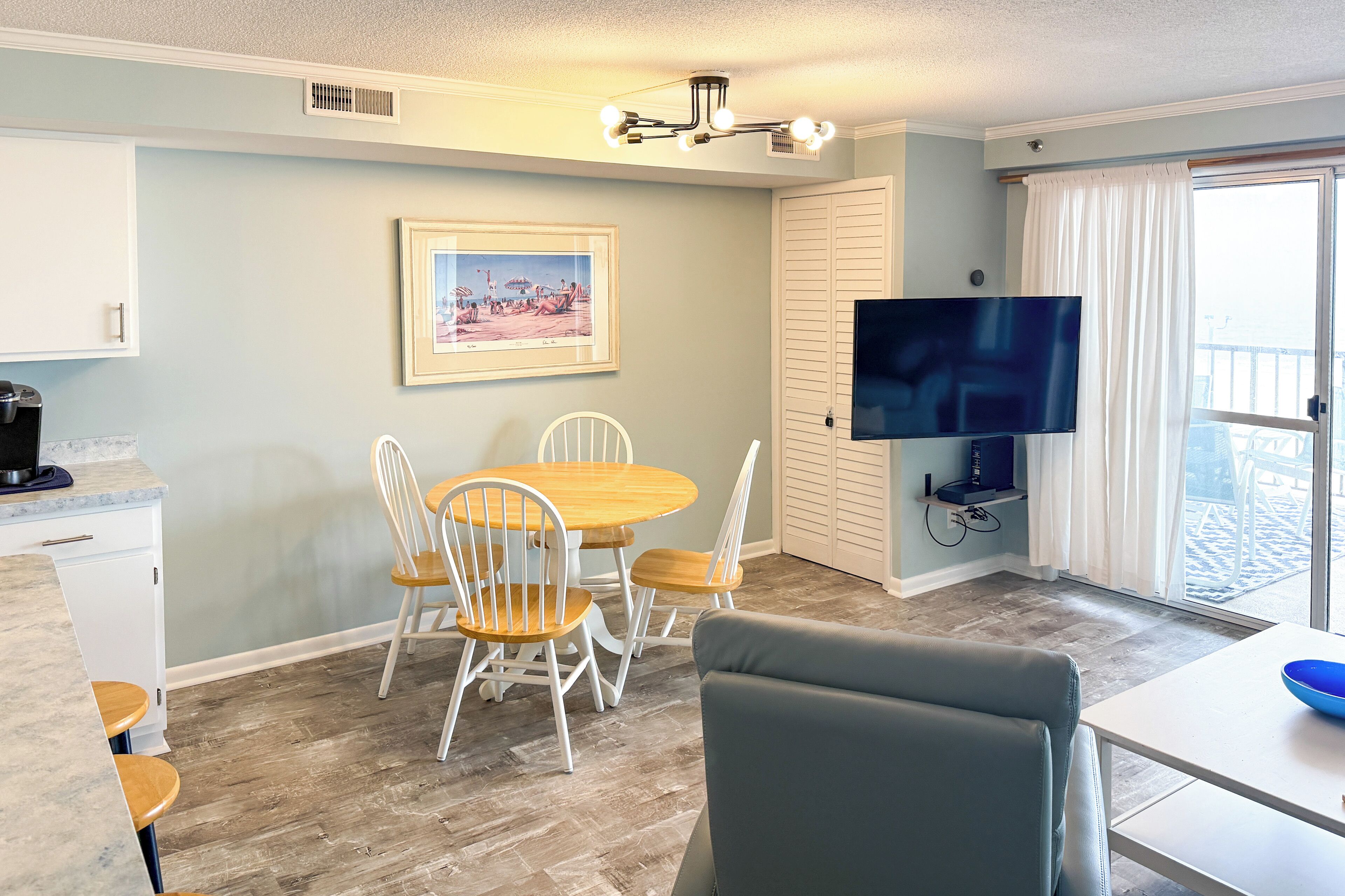 A dining area with a wooden table and chairs, a television, and a window with curtains.