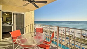 A balcony with a glass table and chairs, a ceiling fan, and a view of the beach and ocean. - Beachfront PCB Escape w/ Free Beach Chair Services (Panama City Beach)
