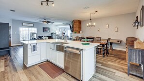Une cuisine spacieuse dotée d’un îlot central, d’un coin repas avec des meubles en bois et d’un ventilateur de plafond.