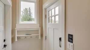 A hallway with a window, a door with a light switch, and a wall-mounted sign.