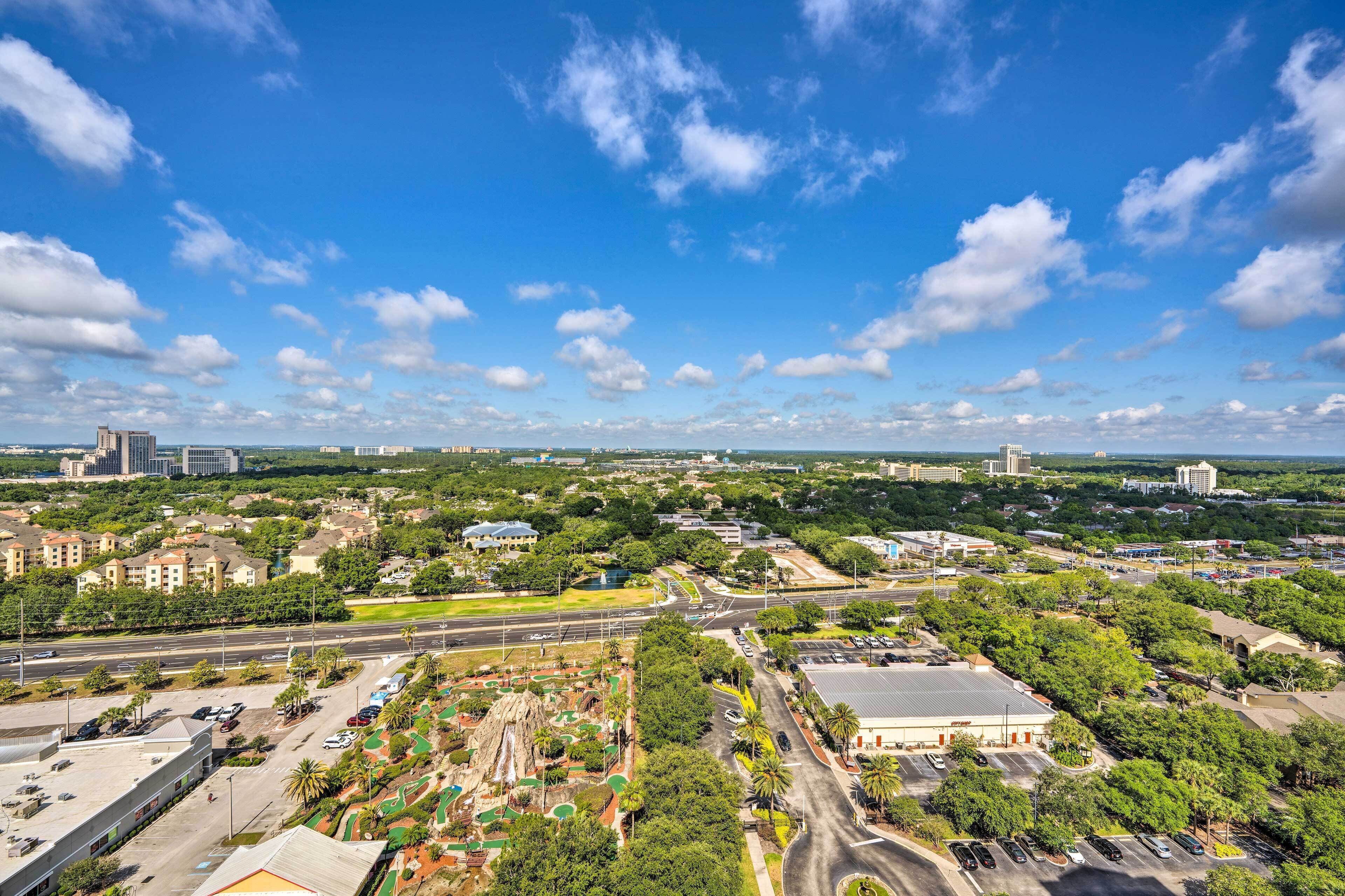 An aerial view of a cityscape with a mix of residential and commercial buildings, roads, and green spaces.