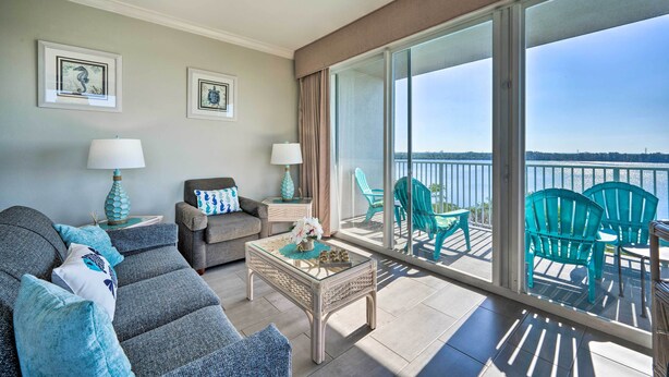 A modern living room with a sofa, coffee table, and chairs, a balcony with a view of the water, and framed artwork on the walls. - ~ 2 Mi to Disney & Universal: Orlando Resort Condo (Orlando)