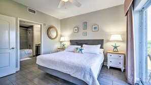 A spacious bedroom with a large bed, a ceiling fan, a bathroom with a bathtub, and a view through a window. - ~ 2 Mi to Disney & Universal: Orlando Resort Condo (Orlando)