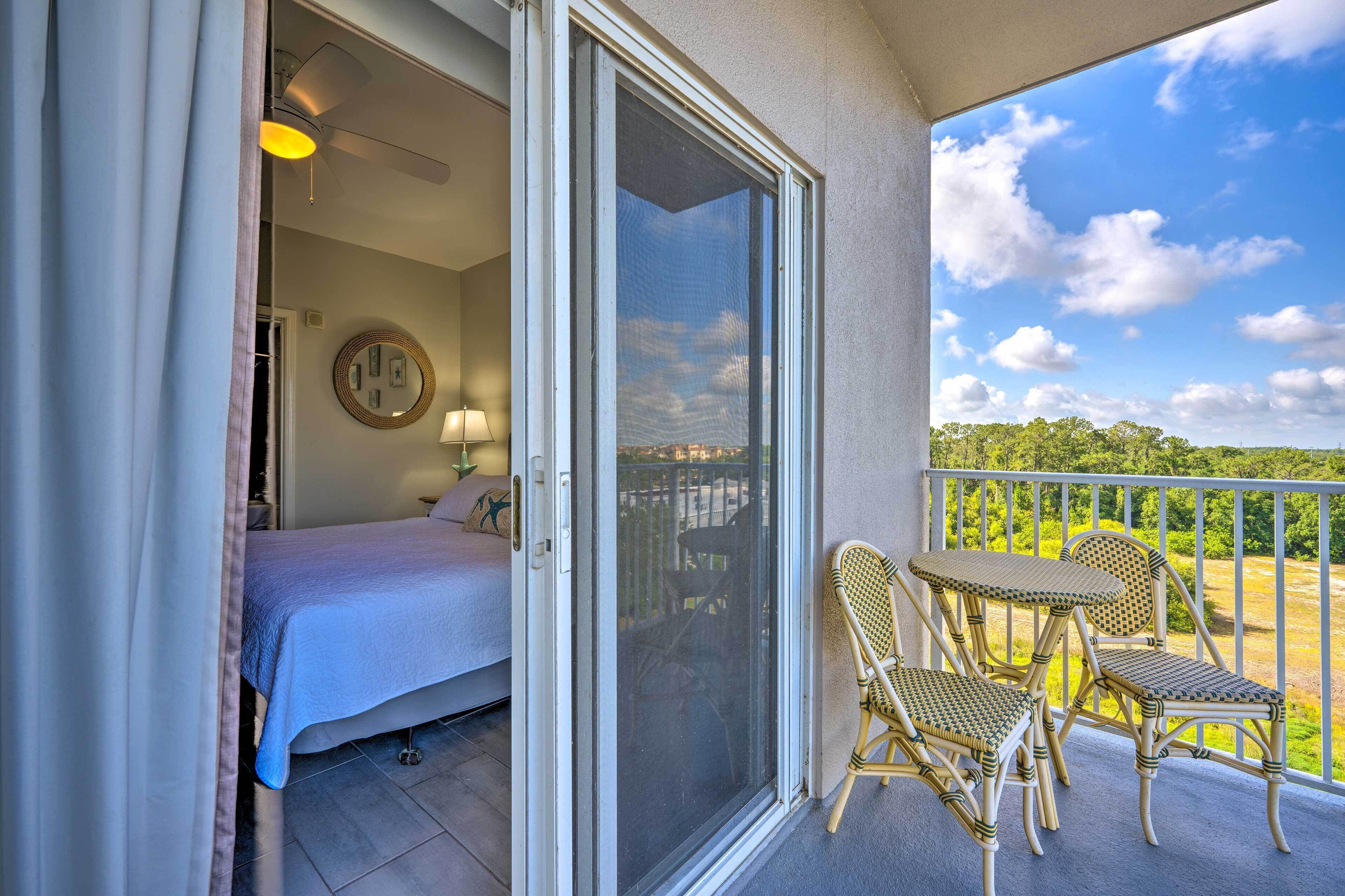 A balcony with a bed, a chair, and a table.