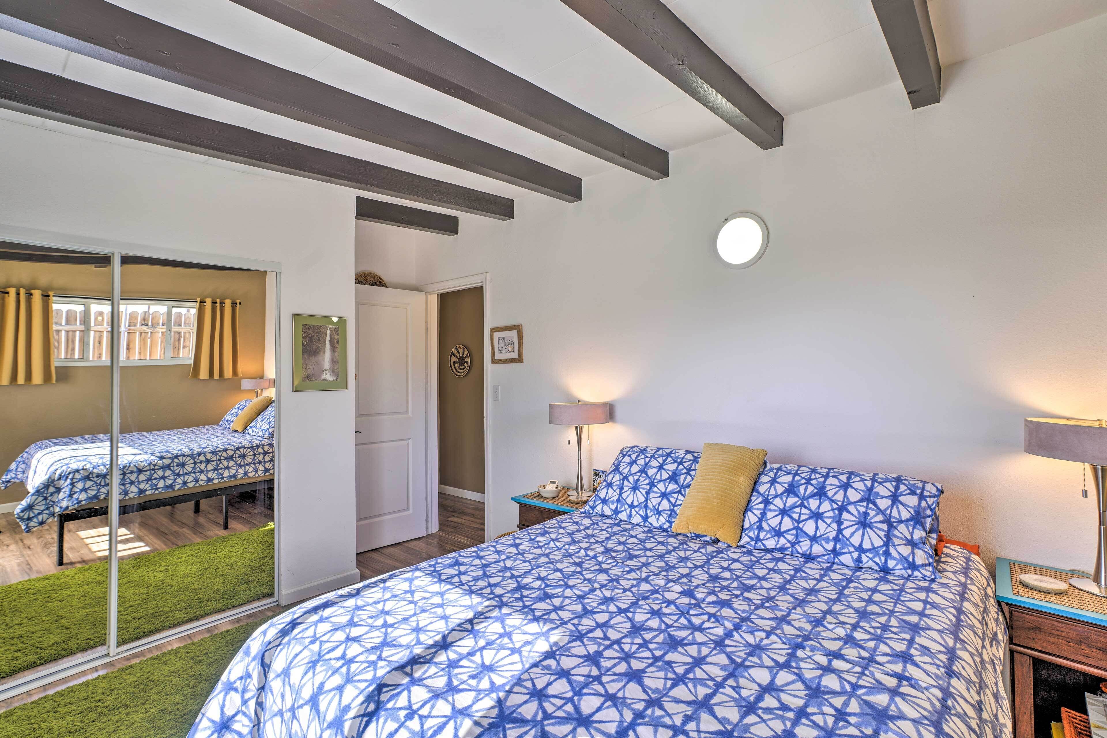 A bedroom with a large bed, a bedside table with a lamp, and a mirror.