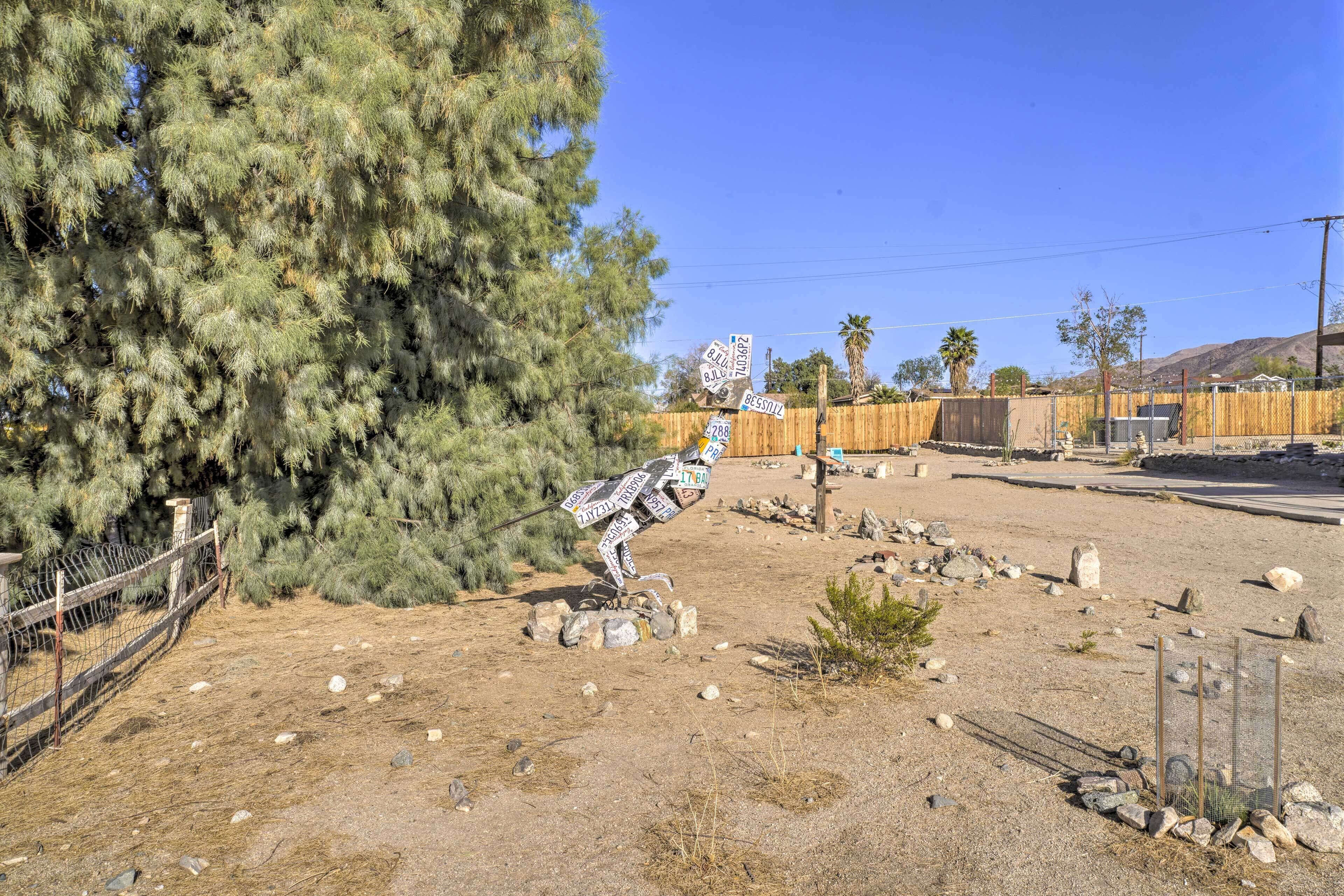 A desert landscape with a wooden fence, sparse vegetation, and a clear sky.