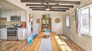 Una cocina moderna con armarios blancos, electrodomésticos de acero inoxidable y una mesa de comedor de madera con sillas azules.