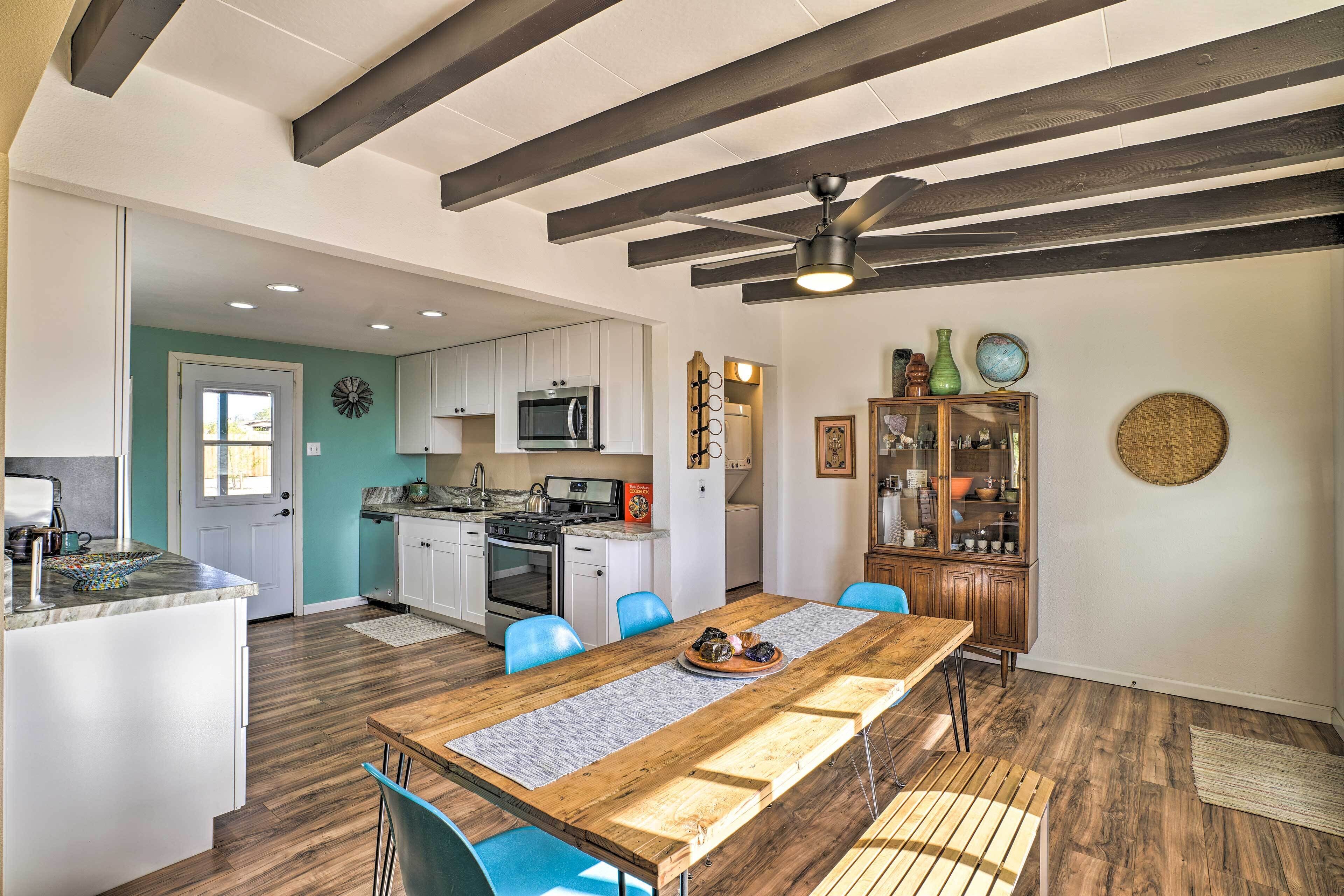 A spacious kitchen with modern appliances, a dining area with a wooden table, and a ceiling fan.