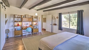 Un dormitorio con una cama grande, un escritorio con silla, una estantería y una ventana con cortinas.